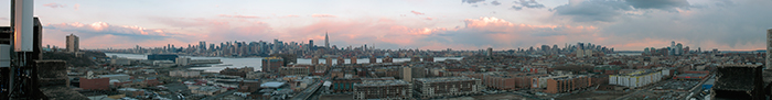 200 degree wide panorama showing entire island of manhattan as well as jersey city and hoboken. warm setting sun catches clouds behing manhattan
