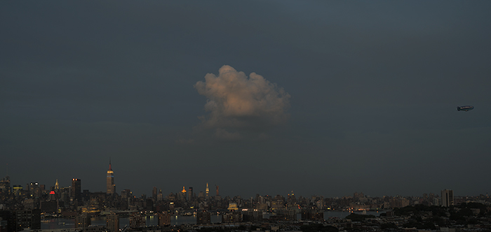 dusk view of new york city showing a lone cloud illuminated by a setting sun